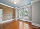 Large bedroom with wood accent wall, hardwood flooring, white-framed windows with curtains, and pale grey walls at 308 W Monroe St, Salisbury, NC 28144