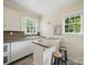 Sun-lit kitchen with gray counter tops, white cabinets, stainless steel dishwasher, and a central island with stools at 308 W Monroe St, Salisbury, NC 28144