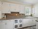 Kitchen features wooden backsplash, white cabinets, gray counter tops, stainless steel dishwasher and artistic decoration at 308 W Monroe St, Salisbury, NC 28144
