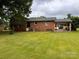 Expansive backyard with well-maintained lawn and mature trees, featuring a brick home with a carport at 6561 Weldon Nw Cir, Concord, NC 28027