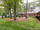 Spacious backyard with mature trees, green grass, and a patio featuring comfortable outdoor seating at 6941 Queensberry Dr, Charlotte, NC 28226