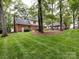 View of spacious backyard featuring patio seating, lush landscaping, and view of the home's exterior at 6941 Queensberry Dr, Charlotte, NC 28226