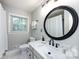Bright bathroom featuring a modern vanity with marble countertop and a round, black-framed mirror at 6941 Queensberry Dr, Charlotte, NC 28226