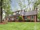 A view of a charming two-story brick home with manicured lawn on a lush, tree-lined lot at 6941 Queensberry Dr, Charlotte, NC 28226