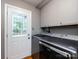 Laundry room with modern washer and dryer, upper cabinets, and exterior door at 6941 Queensberry Dr, Charlotte, NC 28226