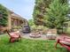 Outdoor space with a fire pit area surrounded by Adirondack chairs, stone walls, and mature landscaping at 705 Woburn Abbey Dr, Fort Mill, SC 29715