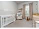 Bright Bedroom with white paneled walls, rocking chair, crib, and window with sheer curtains at 705 Woburn Abbey Dr, Fort Mill, SC 29715