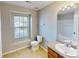 Bright bathroom featuring a single sink vanity, toilet, and window at 8139 Deodora Cedar Ln, Charlotte, NC 28215