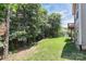 Green backyard with mature trees and a view of the home's exterior at 9011 Kensington Forest Dr, Harrisburg, NC 28075