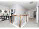 Upstairs hallway with white banister, neutral paint, a mini-fridge, and views to multiple rooms at 9011 Kensington Forest Dr, Harrisburg, NC 28075