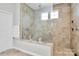 A walk-in shower with stone tile surround, glass partition, and shower niche at 9011 Kensington Forest Dr, Harrisburg, NC 28075