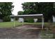 Covered carport on a paved driveway with additional storage buildings in the background, surrounded by greenery at 908 Ravendale Dr, Charlotte, NC 28216