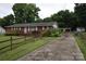 Quaint one-story brick house with a long driveway and ample parking space, set amongst green foliage at 908 Ravendale Dr, Charlotte, NC 28216