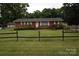 Charming one-story brick home with a well-manicured front yard and a rustic wooden fence at 908 Ravendale Dr, Charlotte, NC 28216