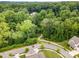 An aerial view of a residential street with a landscaped median and a lush green canopy of mature trees at 915 Claires Creek Ln, Davidson, NC 28036