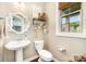 Charming half bathroom featuring pedestal sink, toilet, dark hardwood floors, window and decorative mirror at 915 Claires Creek Ln, Davidson, NC 28036