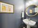 Charming powder room with pedestal sink, gold accents, and stylish framed art for an elegant touch at 1061 Woodglen Ln, Matthews, NC 28104