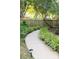 A charming pathway lined with lush greenery leads to a gated wooden fence in a serene setting at 1115 Maremont Ct, Matthews, NC 28104