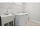 Well-equipped laundry room featuring a utility sink, modern washer, and dryer with functional overhead shelving at 1213 Margo Mannor Dr, Fort Mill, SC 29708