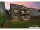 Backyard view of brick home with balcony, stone landscape features, and green lawn at 1280 Winged Foot Dr, Denver, NC 28037