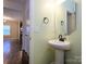 Bathroom featuring a pedestal sink, mirror, and fixtures, with a view into the hall at 13022 Hill Pine Rd, Midland, NC 28107