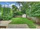 Well-maintained backyard featuring a green lawn, mature trees, a privacy fence, and a storage shed at 1315 Charles Ave, Charlotte, NC 28205