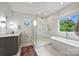 Beautiful bathroom featuring double vanity, free standing tub, and frameless glass shower with natural light at 1315 Charles Ave, Charlotte, NC 28205