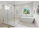 Beautiful bathroom featuring free standing tub and frameless glass shower with natural light at 1315 Charles Ave, Charlotte, NC 28205