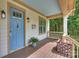 Charming front porch featuring a blue door, wooden floors, brick accents, and a cozy spot for potted plants at 1315 Charles Ave, Charlotte, NC 28205