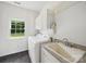 Bright laundry room with white washer, dryer, cabinetry, and utility sink beneath a window at 1340 Canter Ln, York, SC 29745