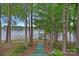 View of a lake through the trees showcasing a private dock and path leading to the water at 145 Hunters Pointe Ln, Mooresville, NC 28117