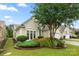 Charming home exterior featuring a well-manicured lawn and landscaped garden beds with a mature tree at 15152 Legend Oaks Ct, Indian Land, SC 29707