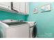 Efficient laundry room with white washer and dryer and teal walls at 15152 Legend Oaks Ct, Indian Land, SC 29707