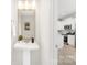 Bathroom features a pedestal sink and a doorway view into the kitchen with white cabinets and appliances at 1815 Wildwood Dr, Charlotte, NC 28214