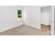 Empty bedroom featuring neutral carpet, a window view of mature trees and a double-door closet at 1815 Wildwood Dr, Charlotte, NC 28214