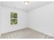 Empty bedroom features neutral carpet and a window view of mature trees in a natural setting at 1815 Wildwood Dr, Charlotte, NC 28214