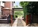 View of the home's brick exterior, driveway, porte-cochere, and wooden gate adding to its curb appeal at 1833 The Plz, Charlotte, NC 28205