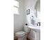 Charming powder room featuring a pedestal sink, round mirror, and natural light from the window at 1833 The Plz, Charlotte, NC 28205