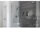 Modern glass shower with sleek gray tile and recessed shelving for storage at 1833 The Plz, Charlotte, NC 28205