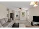 Cozy living room with a comfortable gray couch, light wood flooring, a ceiling fan, and natural light at 1907 Sandal Brook Rd, Fort Mill, SC 29707