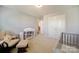 Bedroom with a neutral palette, a changing table with shelves, chair, and crib at 2035 Beacon Ave, Monroe, NC 28110