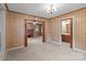 Living room with carpeted floors and wood paneled walls with multiple windows and doorways to other rooms at 3345 Long Ferry Rd, Salisbury, NC 28146