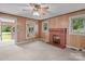 Cozy living room featuring a brick fireplace, carpeted floors, wood panel walls, and multiple surrounding windows at 3345 Long Ferry Rd, Salisbury, NC 28146