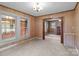 Living room featuring carpeted floors and wood paneled walls with surrounding windows and doorways to other rooms at 3345 Long Ferry Rd, Salisbury, NC 28146