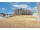 A large backyard featuring a grassy lawn and view of the home's exterior siding and other neighboring homes at 427 Carolina Hemlock Dr, Locust, NC 28097