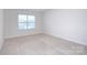 A well lit bedroom with beige carpet and neutral colored walls and a window for natural light at 427 Carolina Hemlock Dr, Locust, NC 28097