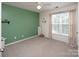 Simple bedroom with large window, neutral carpet and soft green wall providing natural light and cozy atmosphere at 5741 Bentgrass Run Dr, Charlotte, NC 28269