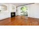 Elegant living room featuring hardwood floors, a fireplace, built-in shelving, and a large arched window at 5809 Sharon Rd # G, Charlotte, NC 28210