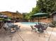 Community pool featuring outdoor seating, tables, umbrellas, lounge chairs, and lush trees at 5809 Sharon Rd # G, Charlotte, NC 28210