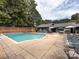 Community pool featuring lounge chairs, umbrellas, tables, and a brick fence for privacy at 5809 Sharon Rd # G, Charlotte, NC 28210